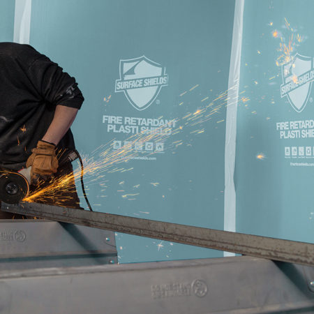 A man uses a metal polishing machine as filings fall onto a protective surface.