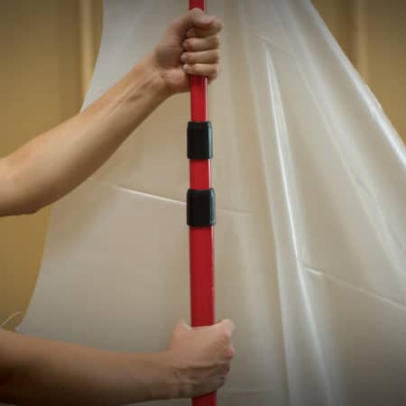 A person's hands holding a red and black pole.